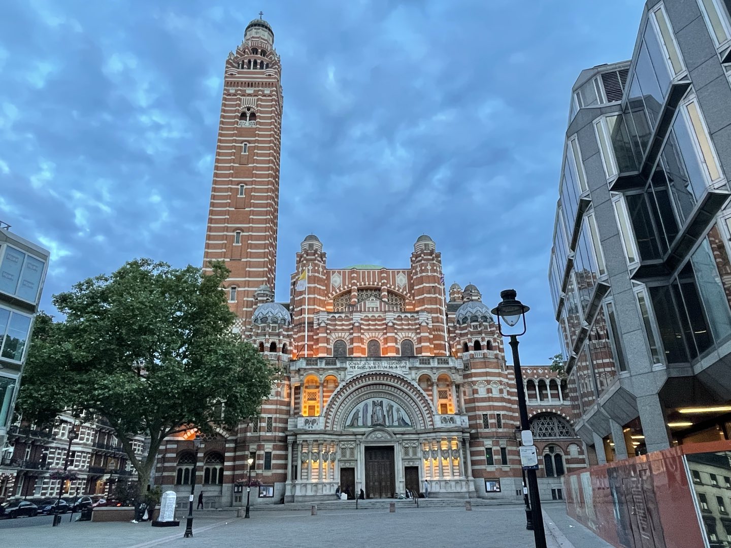 A brick cathedral with a tall campanile lit at dusk
